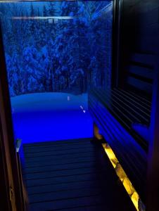 ラ・マルベーにあるChalet Pôle Nord - Luxe Exceptionnel, Spa et Saunaの窓の前にある青い照明の浴槽