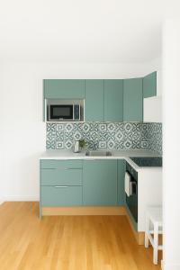 科尔贝埃索讷Omega Appartment的厨房配有蓝色橱柜和微波炉