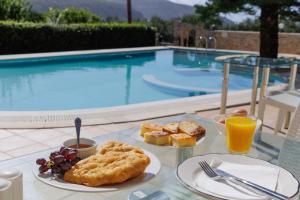 a table with plates of food and drinks and a pool at LITHOS by the sea in Neo Itilo