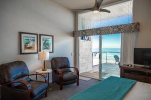 a bedroom with a bed and two chairs and a television at Seashore On The Sand in Carlsbad