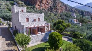 Un antiguo edificio de piedra con una montaña al fondo. en LITHOS by the sea, en Neon Oitilon