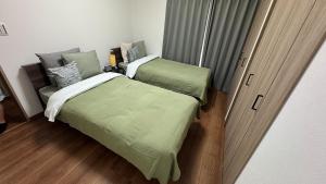 Un dormitorio pequeño con dos camas y una ventana. en 大津町国際交流会館, en Ozu