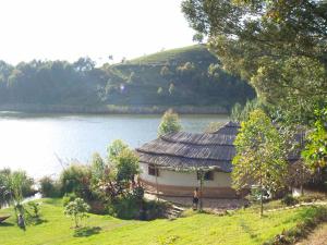 a house next to a lake with a building at Paradise Resort in Chabahinga