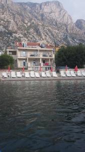 a group of lounge chairs on a beach next to the water at Apartments Pejanović in Kotor