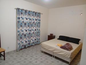 1 dormitorio con cama y ventana con cortina en Pousada recanto das ondas, en Saquarema