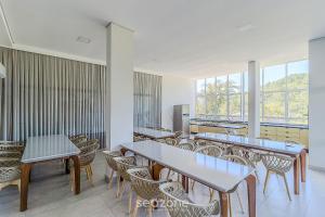 a dining room with tables and chairs and windows at Sua estadia completa a poucos minutos do mar em BC – STLs in Balneário Camboriú