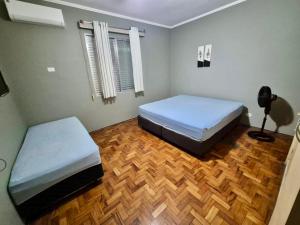 Pé na areia Gonzaguinha São Vicente في ساو فيسينتي: غرفة نوم بسريرين وارضية خشبية