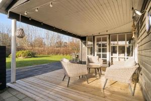 Classic Holiday Home Near Beach And Nature في Grenå Strand: سطح مغطى مع كراسي وطاولة