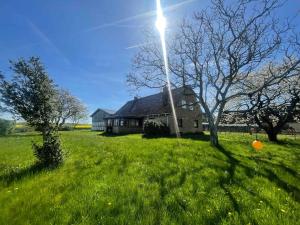 a house in a grassy field with a light pole at Renovated Country Home 50 M From The Sea in Blans