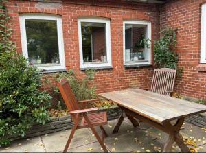 a wooden table and two chairs in front of a brick building at The Coziest Farm Holiday In The Countryside in Tommerup