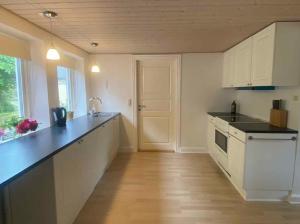 a kitchen with white cabinets and a black counter top at The Coziest Farm Holiday In The Countryside in Tommerup