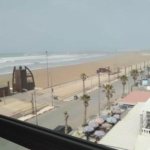 Plage de MehdiaNice apartment by the beach的享有棕榈树和遮阳伞海滩的景致。