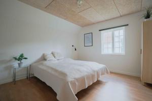 a white bedroom with a bed and a window at Stay In Hindemaes Historic Managers House in Ullerslev