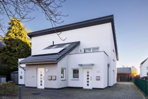 una casa bianca con pannelli solari sul tetto di Modernes City Apartment in Lübbecke mit Terrasse a Lübbecke