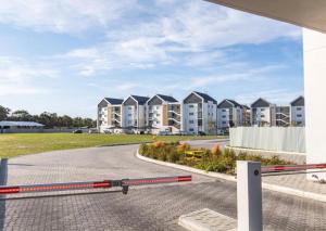 a street with houses in the background with a red and white rail at Beachfront Getaway in Gqeberha