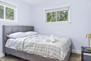 a white bedroom with a bed with two windows at Abby's Place in Fredericton