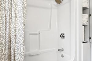 a white bathroom with a shower with a shower curtain at Abby's Place in Fredericton +33 photos
