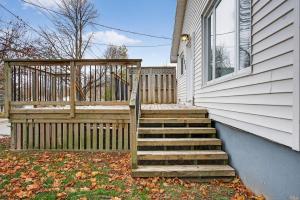 a house with a wooden staircase next to a fence at Cozy 3BR Downtown Fredericton Home with Parking in Fredericton