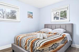a bed in a bedroom with two windows at Cozy 3BR Downtown Fredericton Home with Parking in Fredericton