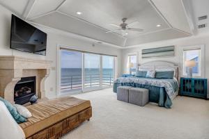 een slaapkamer met een bed, een open haard en een televisie bij Sea Haven - Oceanfront home w pvt beach & deck in Ponte Vedra Beach