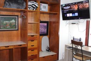 Zimmer mit Holzregalen und einem Flachbild-TV in der Unterkunft Aparthotel Maison Suisse in Asunción