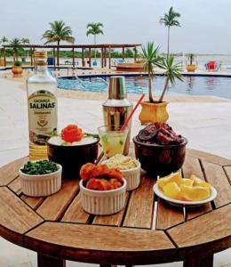 uma mesa com comida e bebidas numa mesa perto de uma piscina em GOLDEN LAKE, lugar para relaxar em Arraial do Cabo