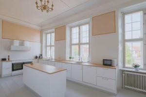 a large kitchen with white cabinets and a chandelier at Hindemae Estate For Holidays And Events in Ullerslev