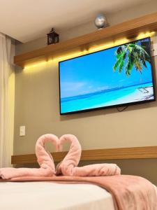 Dos flamencos rosados frente a un televisor de pantalla plana en Magnífico APARTAMENTO de Charme - 3 quartos AR CONDICIONADOS SPLIT - Beira Mar, 2 banheiros, 2 Vagas Garagem, 4 Varandas, 2 Elevadores, Redes para Descanso, Wi-Fi, Air Fryer, Disney Plus, HBO Max, Guarda Sol, Cadeiras de Praia e Caixa Térmica, en Guarapari