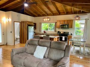 a living room with a couch and a kitchen at Tropical Jungle House in Coxen Hole