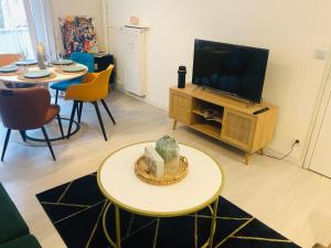 ein Wohnzimmer mit Fernseher und Tisch und Stühlen in der Unterkunft Superbe T3 calme proche de Lille - La Madeleine in La Madeleine