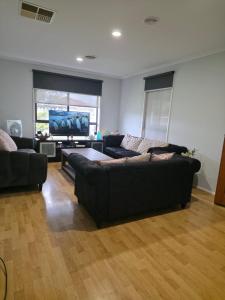 a living room with two couches and a flat screen tv at 4 Westcott Parade Rockbank in Rockbank