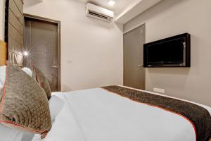 Super Townhouse Siri Residency في بانغالور: غرفة نوم بسرير ابيض وتلفزيون بشاشة مسطحة