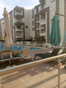 a swimming pool with chairs and umbrellas next to a building at Appartement Neuf au Bord de la Mer - Hammamet Sud Zone Touristique in Hammamet