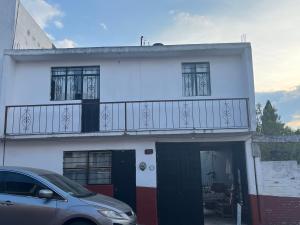 マサミトラにあるCasa Gómezのバルコニー付きのホワイトハウスで、正面に駐車した車を利用できます。