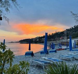 a group of blue chairs and umbrellas on a beach at La vista Azzurra in Bordighera