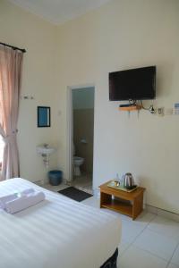 Un dormitorio con una cama y un televisor en la pared. en New Amandani House by Yurooms, en Kejayan