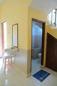 Un baño con lavabo, inodoro y espejo. en New Amandani House by Yurooms, en Kejayan