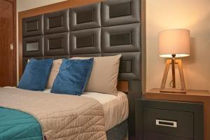 a bedroom with a bed with blue pillows and a lamp at Casa almendros 31 in Ciudad Guzmán