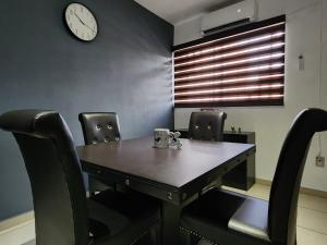 a dining room table with chairs and a clock on the wall at Casa almendros 31 in Ciudad Guzmán
