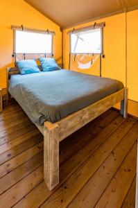 Łóżko w pokoju z drewnianą podłogą w obiekcie Camping - Piscine - ccbbaah w mieście Quinson