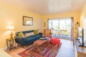 a living room with a blue couch and a television at Boho Cocoa Beach 1BR Steps to Beach in Cape Canaveral