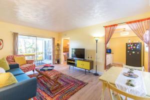 a living room with a blue couch and a tv at Boho Cocoa Beach 1BR Steps to Beach in Cape Canaveral