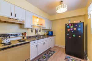 a kitchen with white cabinets and a black refrigerator at Boho Cocoa Beach 1BR Steps to Beach in Cape Canaveral +10 photos