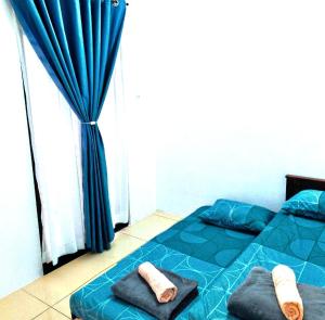 a bedroom with a blue bed with towels on it at PORT DICKSON HomeStay, Family 2 BR Netflix Wifi in Port Dickson