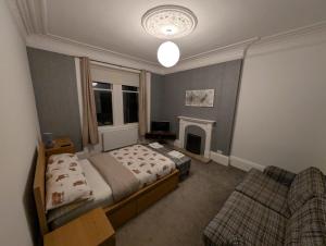 a bedroom with a bed and a couch and a fireplace at Blackthorn Manor in Greenock
