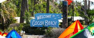 a blue welcome to a cocoa beach sign with kites at 1BR Cocoa Beach Home - 1 Min to Beach in Cape Canaveral