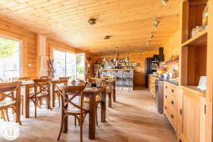 una cocina con techos de madera, mesas y sillas de madera en Chambres D'hôtes Histoire D'anges, en Joursac