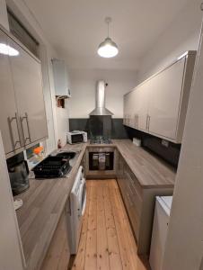 a kitchen with white cabinets and a wooden floor at Blackthorn Manor in Greenock
