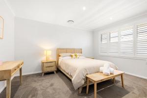 una camera da letto bianca con un letto e una scrivania di Pearl Jervis Bay - Luxury with Swimming Pool a Callala Beach Altre 26 foto