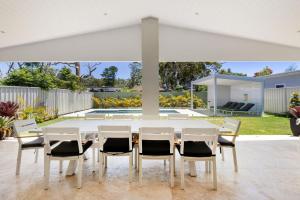 un tavolo da pranzo bianco e sedie sotto un ombrellone bianco di Pearl Jervis Bay - Luxury with Swimming Pool a Callala Beach